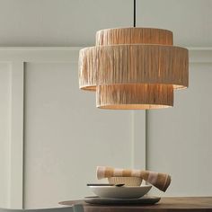 a wooden table topped with a white bowl under a light hanging from a chandelier