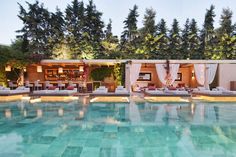 an outdoor swimming pool with lounge chairs and trees in the backgrouds at dusk