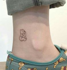 a small tattoo on the ankle of a woman's foot with winnie the pooh