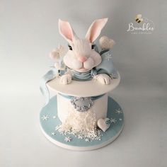 a cake with a rabbit on top and snowflakes around the edges, sitting on a blue plate