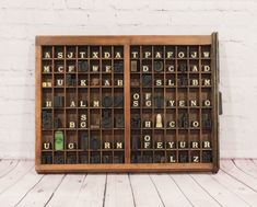 an old wooden typewriter with letters and numbers in it on a white brick wall