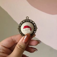 a hand holding a small brooch with a santa hat on it