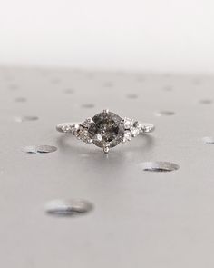 a diamond ring sitting on top of a silver surface with drops of water around it