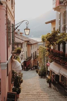 an alley way with flowers and buildings in the background