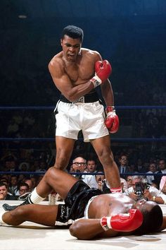 a man laying on the ground next to another man wearing boxing gloves