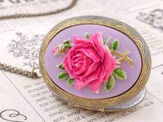 "This is a vintage inspired large rose cameo locket necklace. The beautiful pink fuschia rose with lavender purple background cameo is set on the lace pattern design locket. The cameo necklace is such a romantic classical accessory to keep in your treasure box. The locket can put photos and mementos. It has beautiful engraving designs on both the front and back. The locket size is 50mm x 38mm and the inner size for picture is 35mm x 26mm. It is suspended on a antique brass chain with a lobster c Vintage Rose Design Jewelry As A Gift, Vintage Rose-colored Jewelry For Gifts, Vintage Pink Necklace For Valentine's Day, Vintage Pink Necklaces For Valentine's Day, Vintage Pink Oval Necklace, Elegant Pink Necklace For Keepsake, Elegant Pink Keepsake Necklace, Vintage Pink Jewelry For Keepsake, Vintage Rose Necklace For Gift