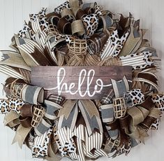 a wreath with the word hello written on it and leopard print bows hanging from the front