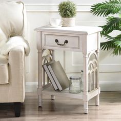 a white end table with some books on it and a potted plant next to it