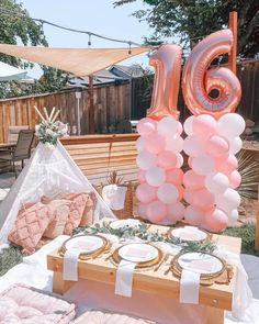 the table is set up with balloons, plates and napkins for an outdoor birthday party