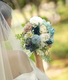 a bride holding a bouquet of blue and white flowers