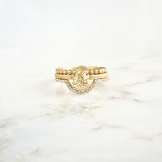 a yellow diamond ring sitting on top of a white marble counter with two gold bands