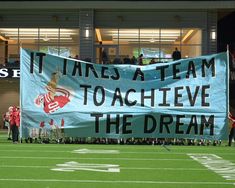 a banner that says it takes a team to achieve the dream on a football field