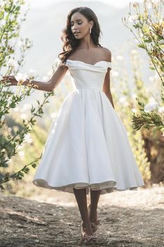 a woman in a white dress is standing outside