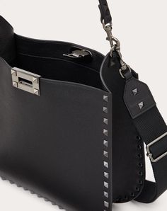 Valentino Garavani Rockstud hobo bag in grainy calfskin. The bag can be handheld or worn over the shoulder using the leather handle or the ribbon shoulder strap, both removable. - Ruthenium-finish studs and hardware - Iconic hook-and-eye closure - Removable leather handle - Adjustable and removable ribbon shoulder strap - Nappa leather lining. Interior: one slip pocket - Protective feet - Shoulder strap drop length: min.41 cm to max. cm / min. 16.1 in. to max. 27.2 69 in. - Dimensions: W20xH26xD Leather Hobo Bag With Top Handle And Gunmetal Hardware, Luxury Hobo Bag With Gunmetal Hardware In Tote Shape, Luxury Hobo Bag With Gunmetal Hardware, Luxury Crossbody Hobo Bag With Gunmetal Hardware, Luxury Hobo Bag With Gunmetal Hardware Crossbody, Designer Pebbled Leather Shoulder Bag, Daily Use Calf Leather Bags With Metal Hardware, Luxury Hobo Bag With Gunmetal Hardware For Shopping, Luxury Pebbled Leather Rectangular Hobo Bag