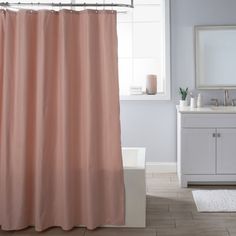 a pink shower curtain in a bathroom next to a white sink and toilet with a mirror on the wall