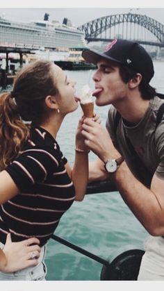 a man and woman eating ice cream by the water