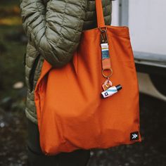 This is not your average tote bag! Designed with life's adventures in mind, this tote bag features sturdy and durable fabric, a zipper pocket inside to keep your valuables safe, and a D-ring on the outside where you can attach your keys and Thread wallet. Carry On with the Thread Tote Bag. Tote Bag Organizer, Thread Wallets, Orange Tote Bags, Unique Wallets, Wrist Lanyard, Lip Balm Holder, Utility Tote, Pouch Organizer, Dog Wear