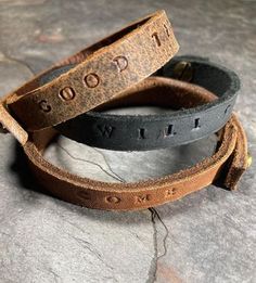 two leather bracelets with the words good and evil written on them sitting on top of a rock