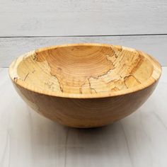 a wooden bowl sitting on top of a white table