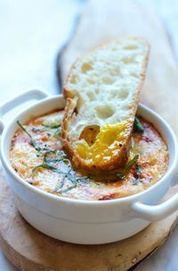 a close up of a bowl of food with bread in it and cheese on top