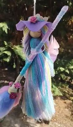 a fairy doll hanging from a tree with two brooms in it's hands