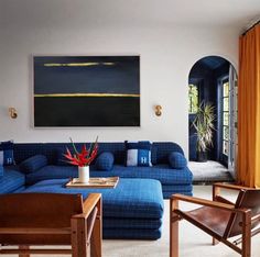 a living room with blue couches and orange curtains