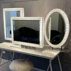 a white table topped with a mirror next to a vanity and stool covered in lights