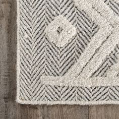 a close up of a rug on a wooden floor with a white and black pattern