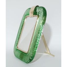 a green and gold mirror sitting on top of a white table next to a metal frame