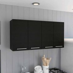 a kitchen with black cabinets and white counter tops is pictured in this image, there are utensils on the stove