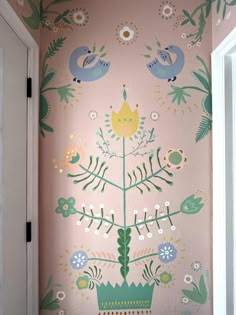 a pink wall with flowers and birds painted on it