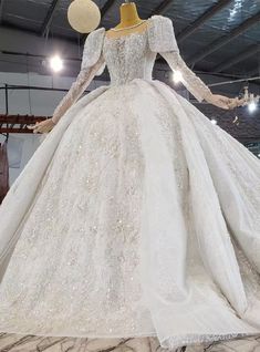 a white wedding dress on display in a room with lots of lights hanging from the ceiling