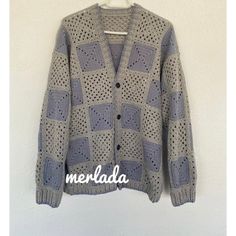 a gray cardigan sweater hanging on a wall with the words meralada written in white