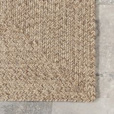 a close up view of a rug on the floor with grey stone tiles in the background