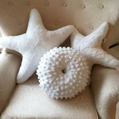 two white starfish pillows sitting on top of a beige chair next to each other