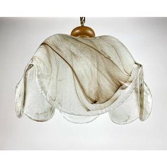 a white hat hanging from a metal hook on a wall with a cloth draped over it