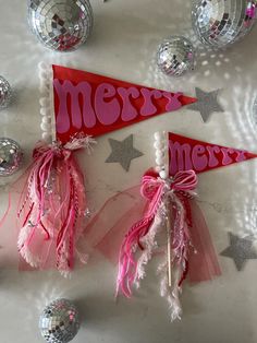 two red and pink merry pennants on a table with silver disco balls, streamers and confetti