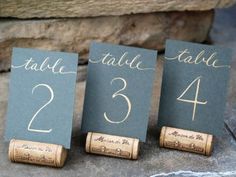 three wine cork place cards with gold numbers on them