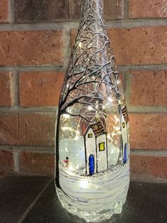 a glass bottle that has some lights in it and is sitting on a table next to a brick wall