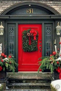 a red front door decorated with wreaths and christmas decorations