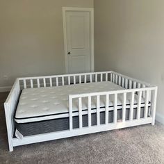 a white crib with a mattress on top in a room next to a door