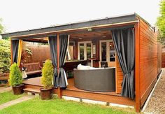 a small wooden shed with curtains on the side and a couch in the back yard