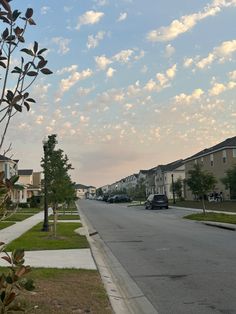 a street lined with houses and trees under a cloudy blue sky