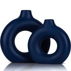 two blue vases sitting next to each other on a white surface, one is shaped like an ovoid