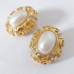 1970s Coro Vendôme gold and pearl oval clip on earrings.  Matte gold-tone metal with swirl motif surround an oval pearlescent stone. Rows of small clear rhinestones are featured around the perimeter.  DESCRIPTION: Material: gold-tone metal, faux pearl, glass rhinestones Colour(s): gold and off white Silhouette: oval Closure: clip on  Style: Formal, business professional, semi formal, classic, timeless, costume jewelry  MEASUREMENTS: Length: 1" Width: 0.75" LABEL/MARKS: Vendôme (a subset of Coro Jewelry Measurements, Style Formal, Business Professional, Formal Business, Matte Gold, Gold Tone Metal, Semi Formal