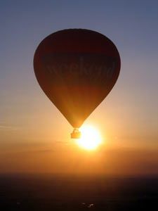 a hot air balloon flying in the sky at sunset