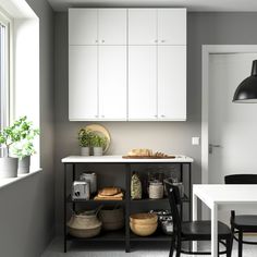 a kitchen with white cabinets and black chairs next to a table in front of a window