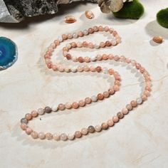 MIX OF SUN/MOON STONE: this beaded mala-style necklace features a mix of genuine peachy sunstone and moonstone beads. These stones pair beautifully together. The moonstone beads are a beautiful milky opaque-white color, while the sunstone displays a characteristic orange peachy color. This mala-style necklace is hand knotted in the champagne color thread. https://www.etsy.com/shop/MYGEMSROCK Spiritual Coral Round Beads Necklace, Spiritual Coral Round Bead Necklaces, Spiritual Coral Necklaces With Round Beads, Spiritual Coral Necklace With Round Beads, Bohemian Peach Round Beads Jewelry, Spiritual Orange Crystal Necklaces With Round Beads, Spiritual Orange Crystal Necklace With Round Beads, Peach Beaded Necklaces With Round Beads, Peach Beaded Necklaces With Round Beads As Gift