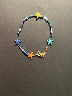 This multicolored starfish anklet has blue beads close to an ocean color. The starfish beads are 14 mm metal. The anklet has a gold clasp closure and an extender. Blue Starfish Charm Anklet For Summer, Blue Anklet With Starfish Charm For Summer, Blue Summer Anklets With Starfish Charm, Blue Beaded Starfish Anklet, Blue Anklets With Starfish Charm For Gift, Blue Anklets With Starfish Charm As Gift, Blue Handmade Star-shaped Beaded Bracelets, Adjustable Blue Starfish Jewelry, Blue Bracelets With Starfish Charm Ocean-inspired