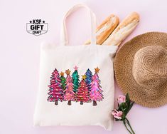 a tote bag with christmas trees on it next to some bread and pink flowers